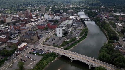 Binghamton city in New York State skyline with downtown buildings and business activity beside river in summer sunlight  