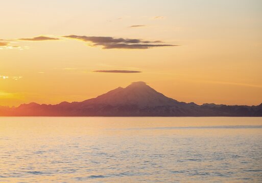 View of Cook Inlet on white mountain peaks of Mount Redoubt at sunset, picturesque golden light of the midnight sun, mountains of the Aleutian Range, Anchor Point, Anchor River State Recreation Area, Alaska, USA