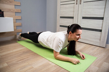 Fototapeta premium Woman performing plank exercise on yoga mat indoors. Fitness routine in apartment. Core strength workout. Healthy lifestyle activity for adults.