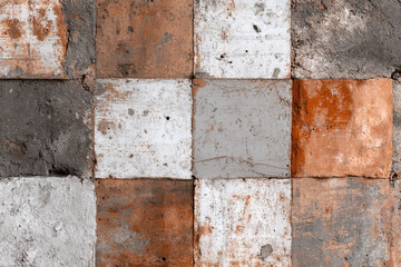 Rough weathered square tiles with a distressed textured finish in orange white and grey