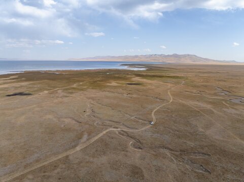Road and off-road vehicle, Aerial view, Vast empty landscape at the mountain lake Song Kul in autumn, Moldo Too Mountains, Naryn region, Kyrgyzstan