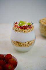 Refreshing layered yogurt parfait in a glass cup, featuring creamy white yogurt, textured rolled oats, sliced strawberries, and vibrant green kiwi fruit pieces for a healthy start.