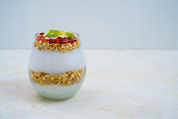 Healthy yogurt parfait layered with golden granola, fresh strawberries, and vibrant kiwi slices presented beautifully in a clear glass