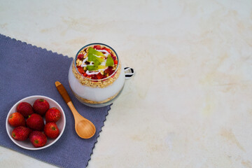 Delicious layered parfait in a clear glass cup featuring yogurt, crunchy oats, fresh strawberries, and vibrant kiwi slices perfectly prepared for a healthy breakfast.