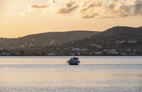 Fishing boat on the sea, behind hill of Paros island, Naoussa, Paros, Cyclades, Greece