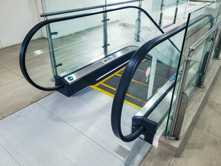 Empty indoor escalator with glass railings and safety markings, highlighting modern public infrastructure, accessibility design, and clean architectural lines in a transit or commercial building.