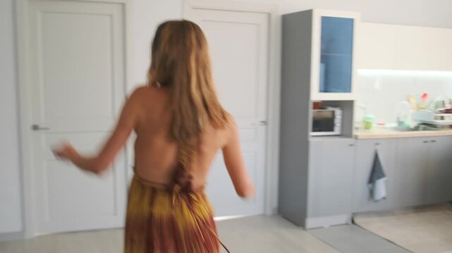 In the bright apartment kitchen an attractive woman in a long orange s