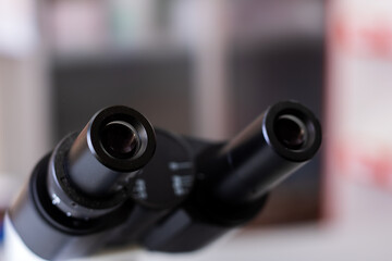 Sharp image focusing on microscope eyepieces with softly obscured lab environment in background