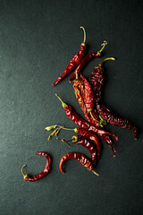 Dry chili peppers on dark stone background. Top view. Copy space