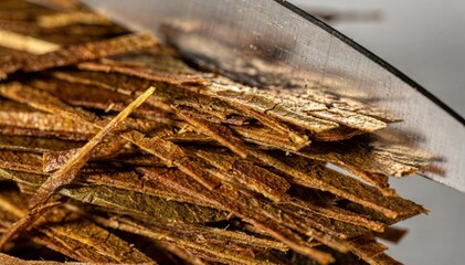 Closeup medium shot focusing on the precise cutting of mediumcut tobacco leaves highlighting the even strips and subtle moisture reflecting light.