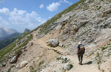 hiker with backpack and sun hat european alps dolomites mountain group northern italy summer