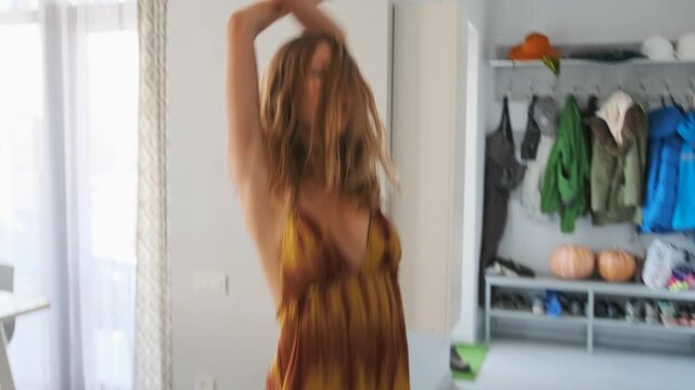 A woman in an orange printed sundress takes a break from remote work a