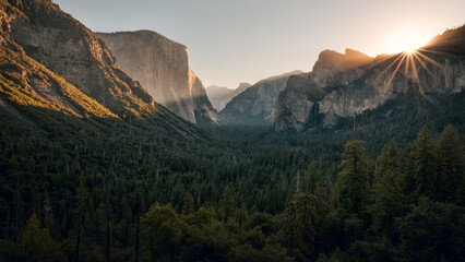 View of Yosemite Valley from Tunnel View point at the moment of sun rising above Cathedral Rocks with massive of El Capitan and half Dome lit by sun, Yosemite National Park, California, USA