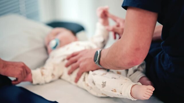 Close up of a caregiver lifting a baby's leg, with focus on the infant's foot and soft background blur