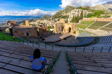 One Woman sitting in the famous greek Theater of Taormina (Sicily, Italy) at sunrise in the early morning hours
