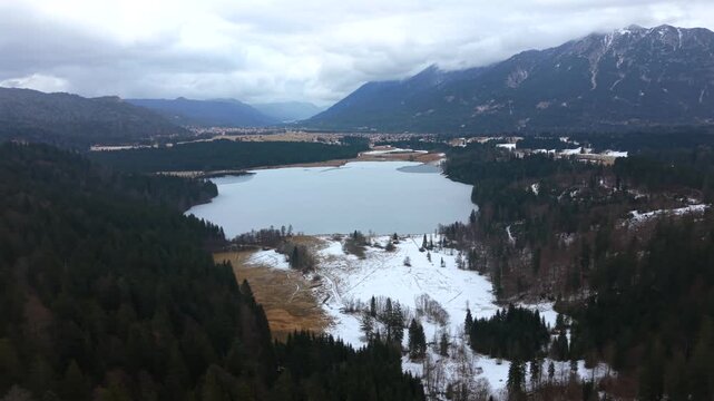 Aerial view of Barmsee lake in the district of Garmisch-Partenkirchen, Bavaria. Winter drone video shows icy water, light snow and alpine scenery near Mittenwald.