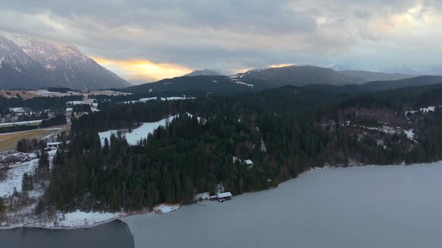 Aerial view of Lake Barmsee in the Bavarian Alps, Germany. Winter drone footage shows calm nature, icy water and alpine scenery from above. Frozen alpine lake near Mittenwald, captured from air.