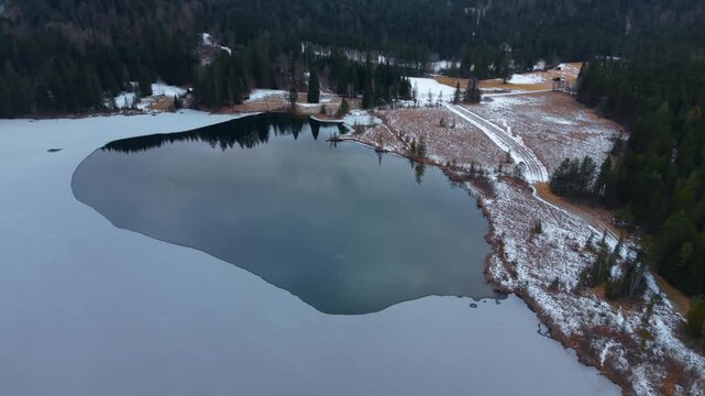 Aerial drone video of Barmsee in southern Germany. Winter conditions show frozen lake and pristine alpine nature near Kruen. Flying over the frozen water of Lake Barmsee, North of Mittenwald.