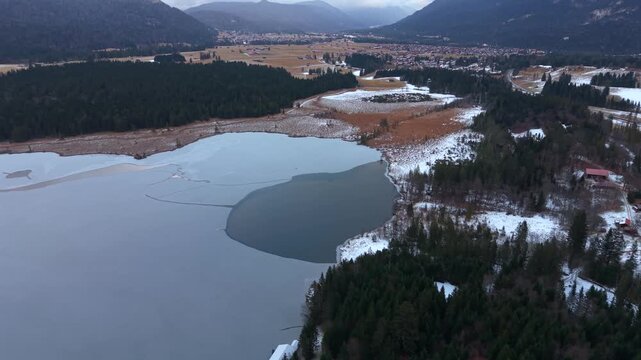 Luftaufnahme per Drohne vom Barmsee in Bayern, Deutschland. Winterliche Landschaft mit teilweise gefrorenem Bergsee nahe Kruen noerdlich von Mittenwald und den Karwendel Bergen.