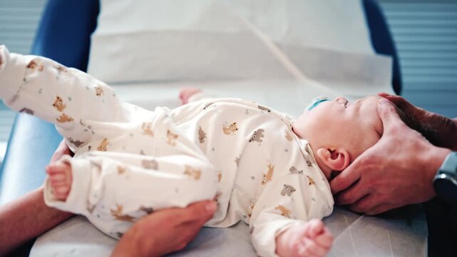 Calm baby wearing a pacifier lying on a medical or therapy table during a pediatric session