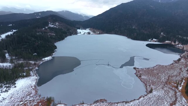 Luftansicht Barmsees in Bayern, Deutschland. Winterliches Drohnenvideo eines ruhigen Bergsees mit gefrorener Wasseroberflaeche und Alpenpanorama. Drone video of Barmsee lake in Oberbayern, Germany