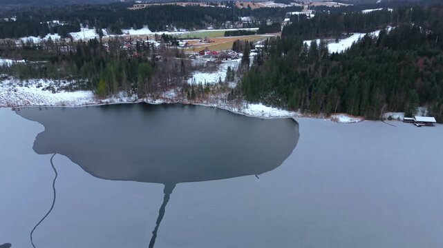 Drone video of winter landscape at Barmsee in Bavaria. Frozen alpine lake surrounded by forest and meadows near Mittenwald, captured from the air. Luftaufnahme vom Barmsee in Bayern, Deutschland.
