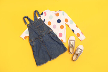Flat lay composition with stylish child clothes and shoes on yellow background