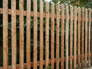 Traditional garden fence made of natural wood, vertical stakes and horizontal rails. Rustic, open design. Copyspace.