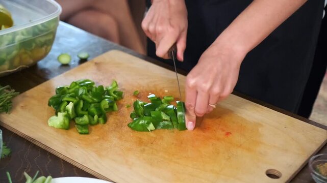 Close-up of a fresh green Ramiro pepper being cut into small pieces wi