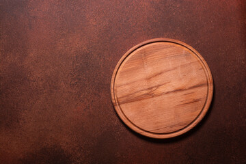 round wooden cutting board on brown background