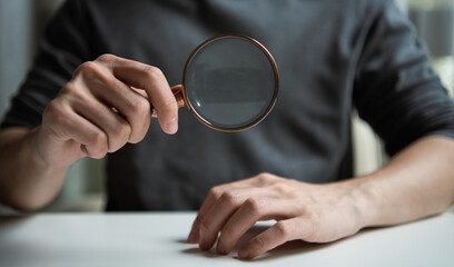 Hands holding magnifying glass. Professional man searching for solutions. Concept of data analysis, security audit, web research, quality control, and finding truth