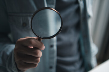 Hand holding a magnifying glass for concept of investigation, discovery, search data, research, seo and professional scrutiny for business marketing trends