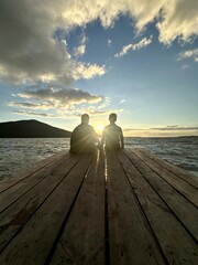 Quiet couple sharing intimate time on wooden pier during sunset