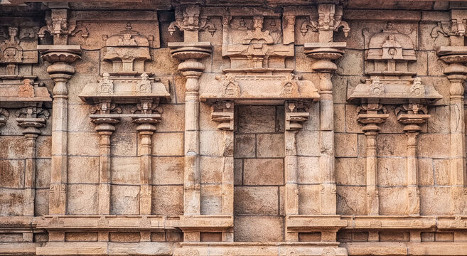 Detailed stone carvings and miniature shrines on a Hindu temple wall at Thiruvathavur, Madurai, Tamil Nadu, showcasing skilled craftsmanship