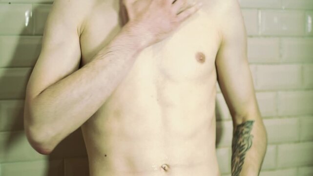 An attractive thin man washes in the shower