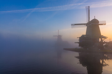 Windmills in morning fog at sunrise in Zaanse Schans. Beautiful sky and iconic silhouettes...