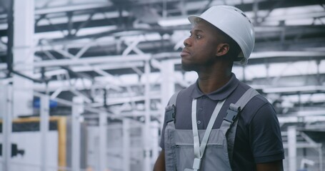 Industrial Male Engineer Walking Through Modern Factory Floor and Inspecting Automated Production Lines and Robotic Equipment, Monitoring Workflow Efficiency and Smart Manufacturing Processes.