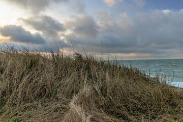 Dramatische K&uuml;stenlandschaft mit Sandd&uuml;nen und wechselhaftem Himmel