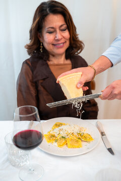 Grating parmesan cheese over fresh ravioli pasta at home dinner