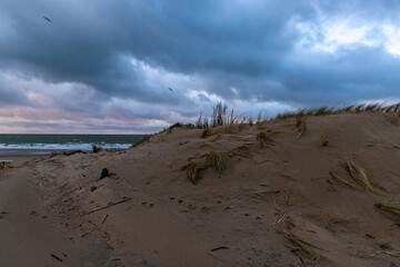 Dramatische K&uuml;stenlandschaft mit Sandd&uuml;nen und wechselhaftem Himmel