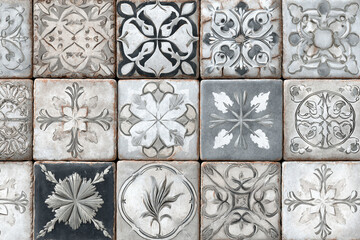 an intricate pattern of vintage ceramic tiles featuring floral and geometric motifs in gray and cream tones