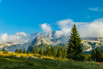 Fototapeta premium Dolomite mountain range landscape with clouds and green grass