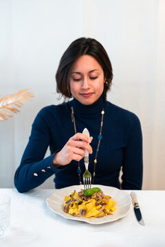 Woman eating homemade tagliatelle pasta with mushrooms at home