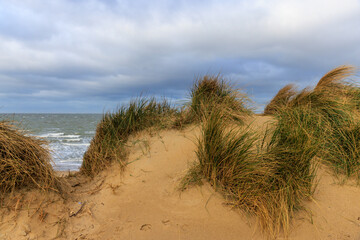 Dramatische K&uuml;stenlandschaft mit Sandd&uuml;nen und wechselhaftem Himmel