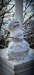 A whimsical snowman on a stone pedestal