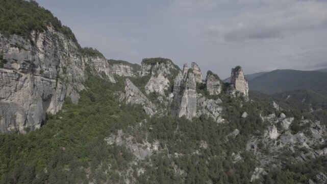 Aerial drone shot gliding past the Sairme Pillars in Lechkhumi, Georgia, revealing towering rock formations surrounded by green hills and untouched Caucasus nature. High-quality 4K footage.