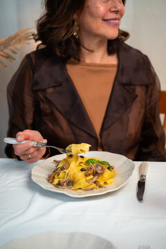 Vertical lifestyle photo of mature woman enjoying homemade Italian pasta during cozy dinner