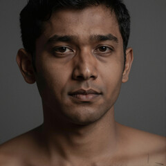 Obraz premium Portrait of a South Asian man with a subtle mysterious expression under dramatic low-key lighting