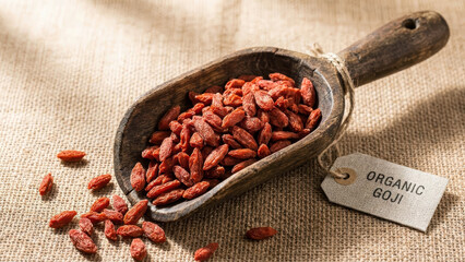 Overhead View Of Organic Antioxidant Goji Berries In Wooden Scoop With Price Tag Label On Rustic Burlap Background