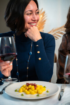 Vertical Portrait of Smiling Woman Enjoying Italian Gnocchi and Red Wine at Cozy Dinner Table
